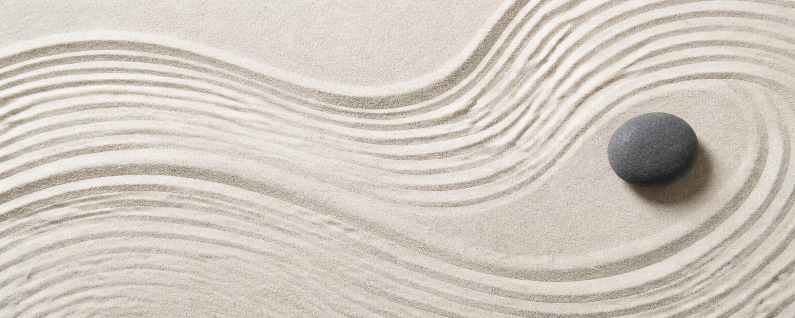 Raked zen garden sand with a single smooth stone